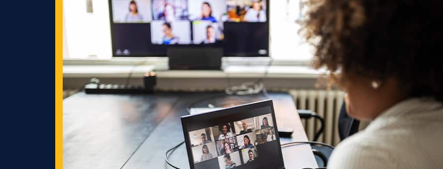 A woman looking at a group of her students on a laptop screen during the online portion of a blended learning experience.