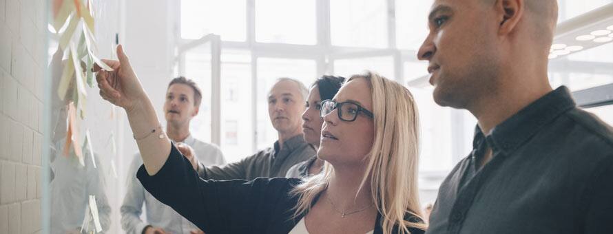 Business professionals in a meeting looking at a whiteboard