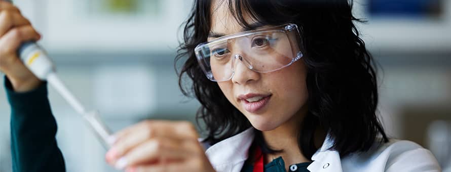 A woman in a STEM profession, holding a test tube and wearing safety goggles.