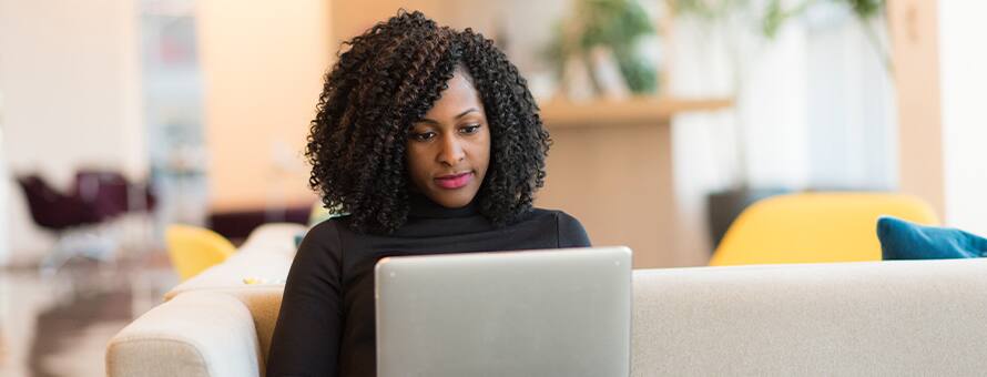 A woman sitting and writing an effective resume on a laptop