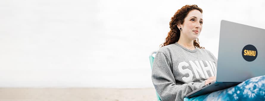 SNHU student working on her laptop at the beach.