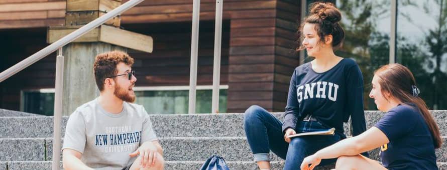 Three SNHU students sitting outside on the steps of a campus building