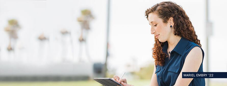 Mariel Embry, a 2022 graduate of SNHU's online BA in Creative Writing degree program, writing on a tablet. 