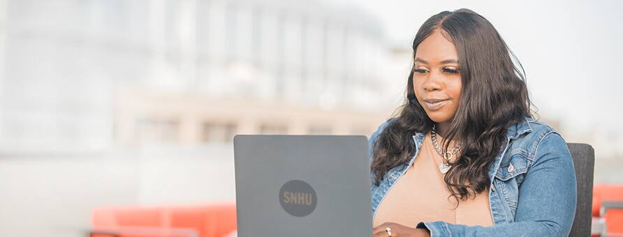 A woman typing on a laptop and smiling