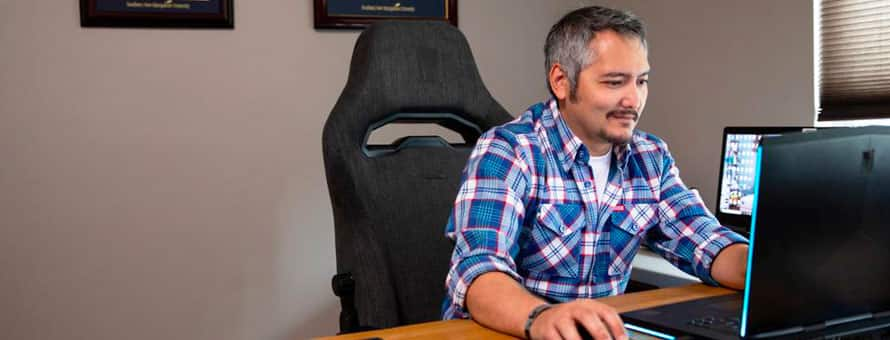 An SNHU student in an office working at a computer