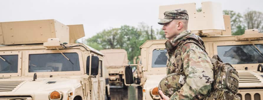 Picture of a soldier with Humvees in the background