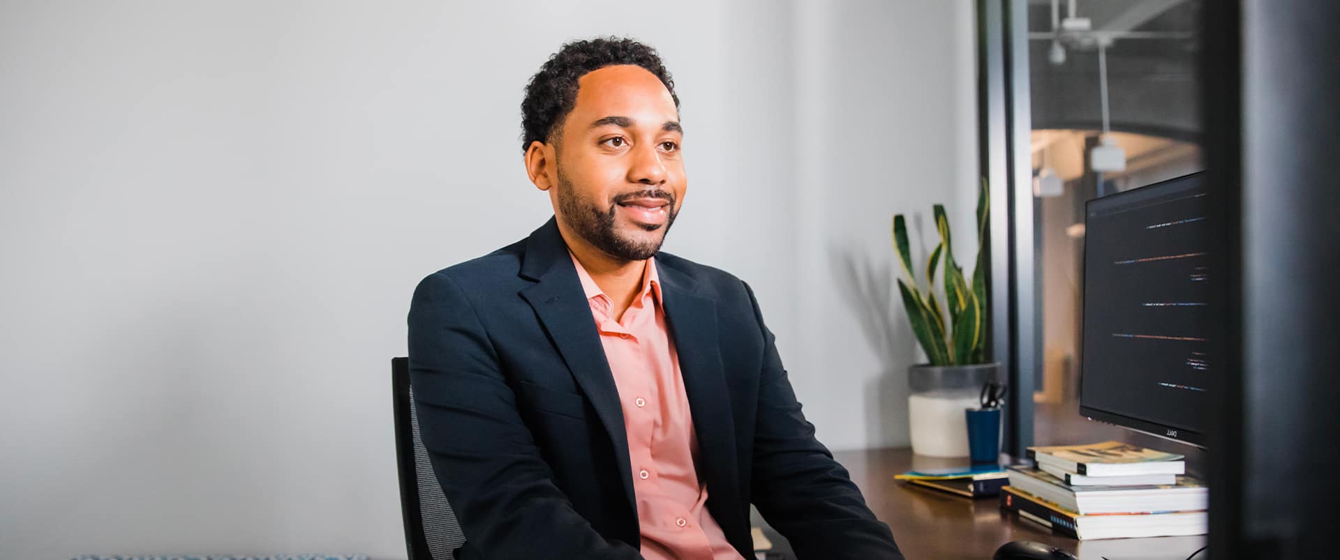 SNHU Grad, donning a blazer, works at his office desk