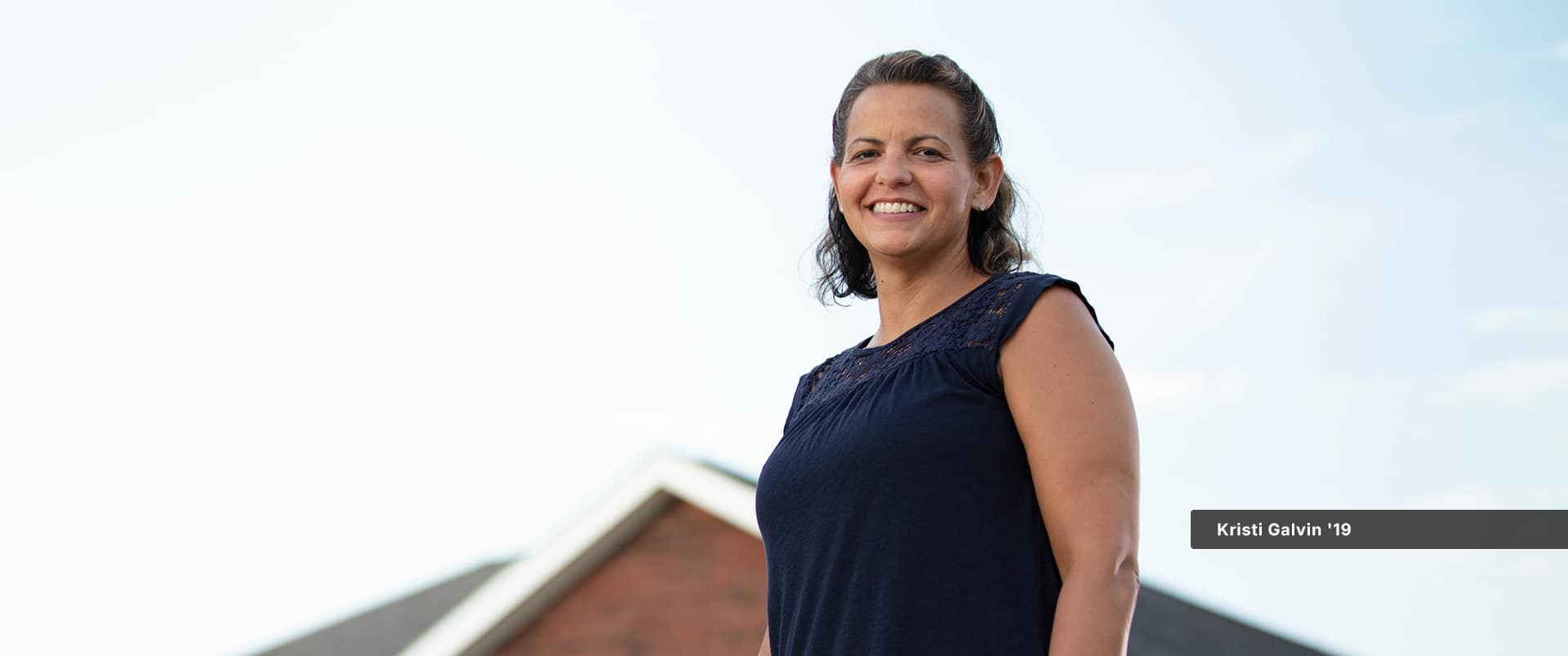 Kristi Galvin, who earned her online degree in human resources, standing in front of a house.