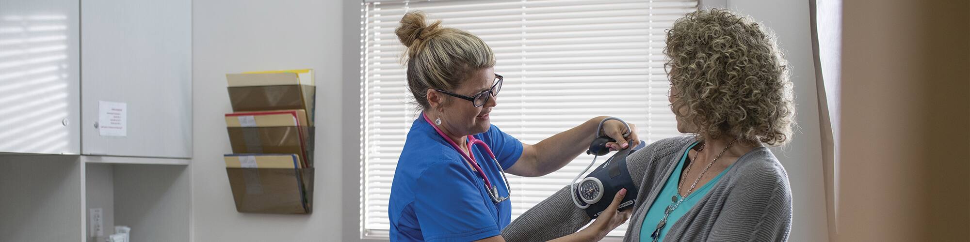 SNHU graduate Kristina Libby putting a blood pressure monitor on a patient in a doctor's office