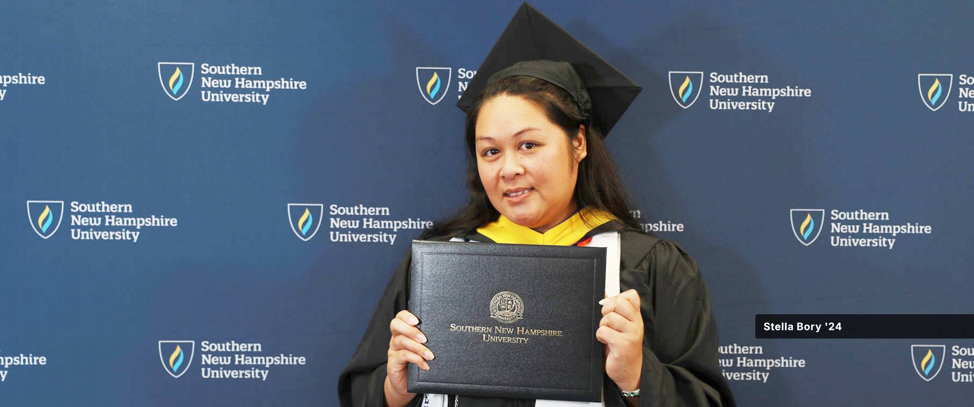Stella Bory, who earned her certificate in HR from SNHU, wearing her cap and gown and holding her diploma.