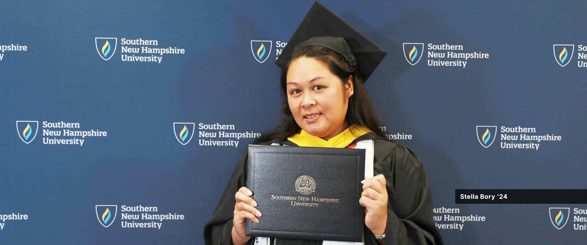 Stella Bory, who earned her certificate in HR from SNHU, wearing her cap and gown and holding her diploma.