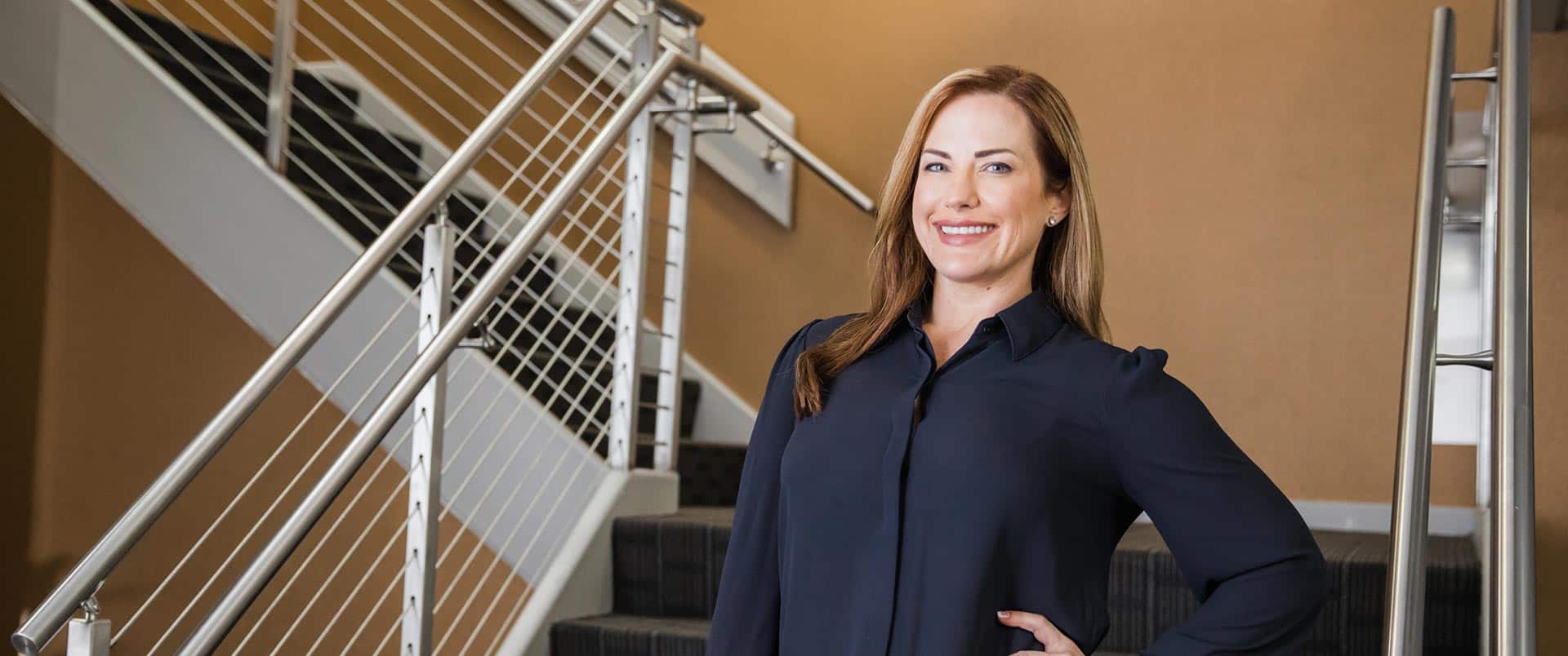 Nikki Bennet, who earned her degree from SNHU, wearing a dark blouse posing in a stairwell.