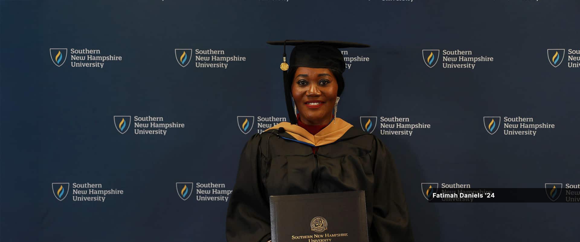 Fatima Daniels, who earned her MBA in project management from SNHU in 2024, wearing her cap and gown and holding her diploma.