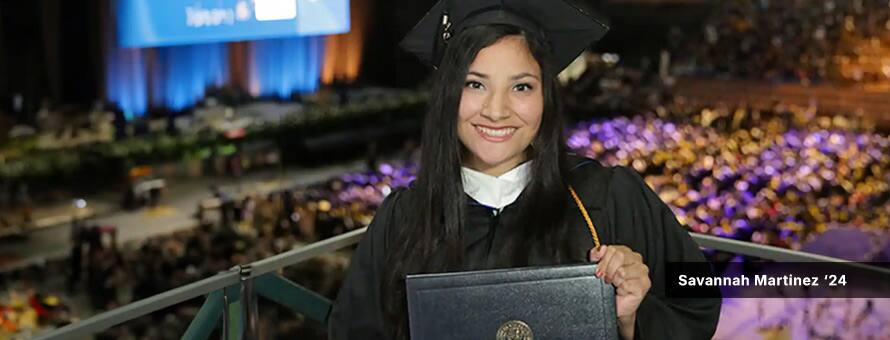 Savannah Martinez, who studied psychology at Southern New Hampshire University, in a cap and gown while holding her diploma at SNHU's 2024 commencement ceremony.
