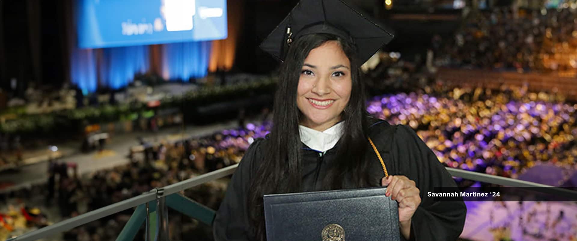 Savannah Martinez, who studied psychology at Southern New Hampshire University, in cap and gown while holding her diploma at SNHU's 2024 commencement ceremony.