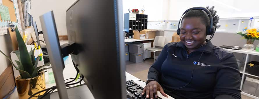 A student support staff member at Southern New Hampshire University (SNHU) smiling while on a call with a student.