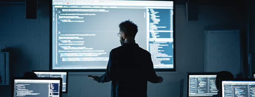 A person with a master's in computer science reviewing code on a big screen for his job