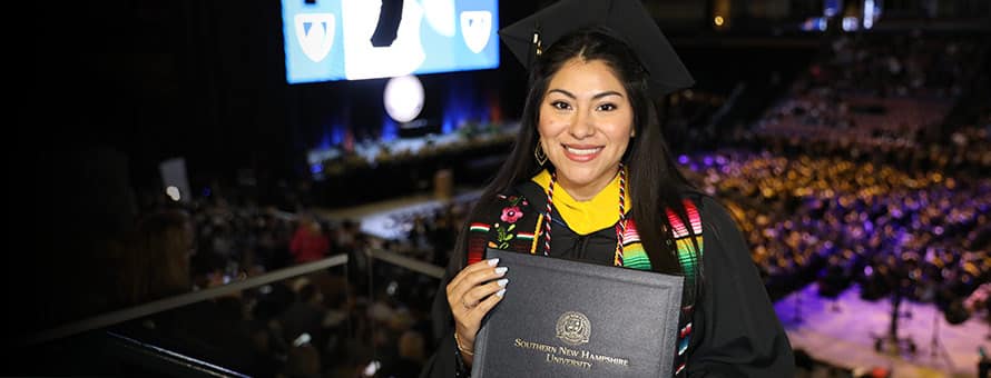 Eliana Cornejo, a 2023 graduate pf SNHU's bachelor's in business administration program, holding her diploma at graduation