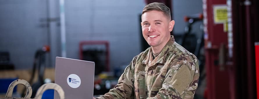 SNHU graduate and U.S. Army Reserve trainer coach Rob Thomas doing college coursework on a laptop.