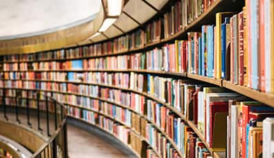 Many colorful books in a curved bookshelf