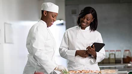 Sierra Ingram, who graduated online college at Southern New Hampshire University, in a kitchen discussing strategy with a chef