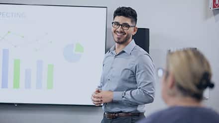 2020 SNHU graduate Naeem Jaraysi, presenting a chart in a workplace setting.