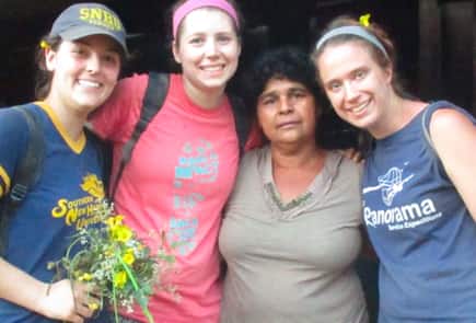 Three SNHU students posing with a member of the community during volunteer work