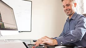 Business professional sitting at a desk and smiling while typing