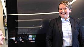 Business professional standing in a meeting setting and smiling