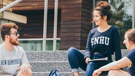 A group of master's degree students gathered on steps outside at Southern New Hampshire University's Manchester campus