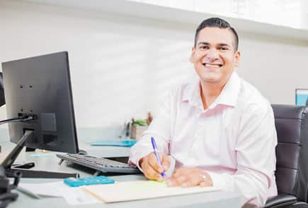 A man writing notes on paper and smiling