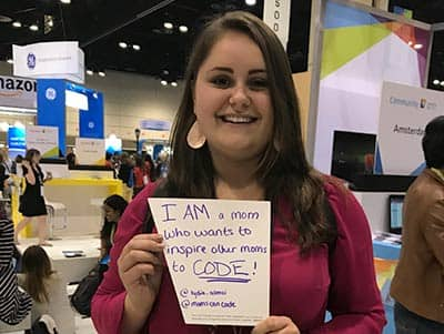 Lydia Alonci at the Grace Hopper Celebration holding a sign reading I'm a mom who wants to code.