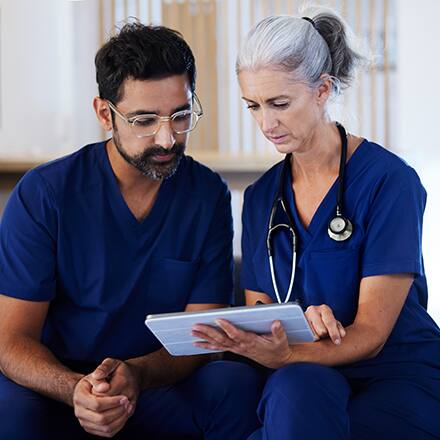 Three healthcare professionals assessing a patient on a hospital bed
