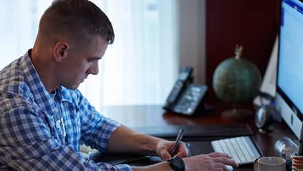 Student sitting at his desk on his computer doing course work