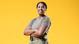 An SNHU military student standing in front of a yellow background