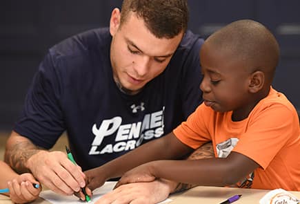 SNHU student drawing with a child during youth programming at the Center for New Americans