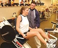 A trainer instructing a student on using weight lifting equipment