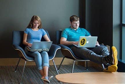 Two campus students using their laptops to complete school work