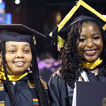 Diane Sanda, left, and Samiyah Muhammed, right, dressed in their SNHU graduation cap and gown.